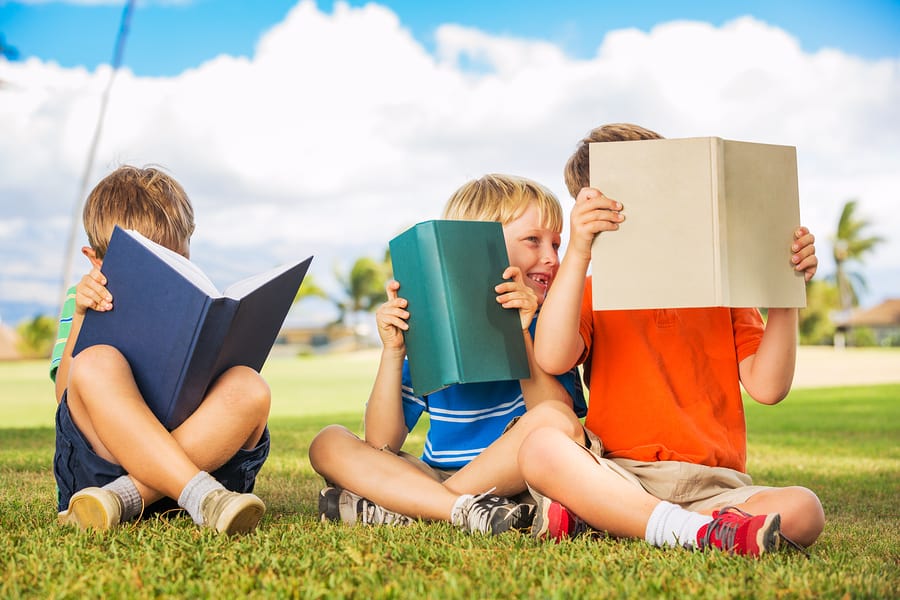 Group of happy kids reading books outside, friendship and learni