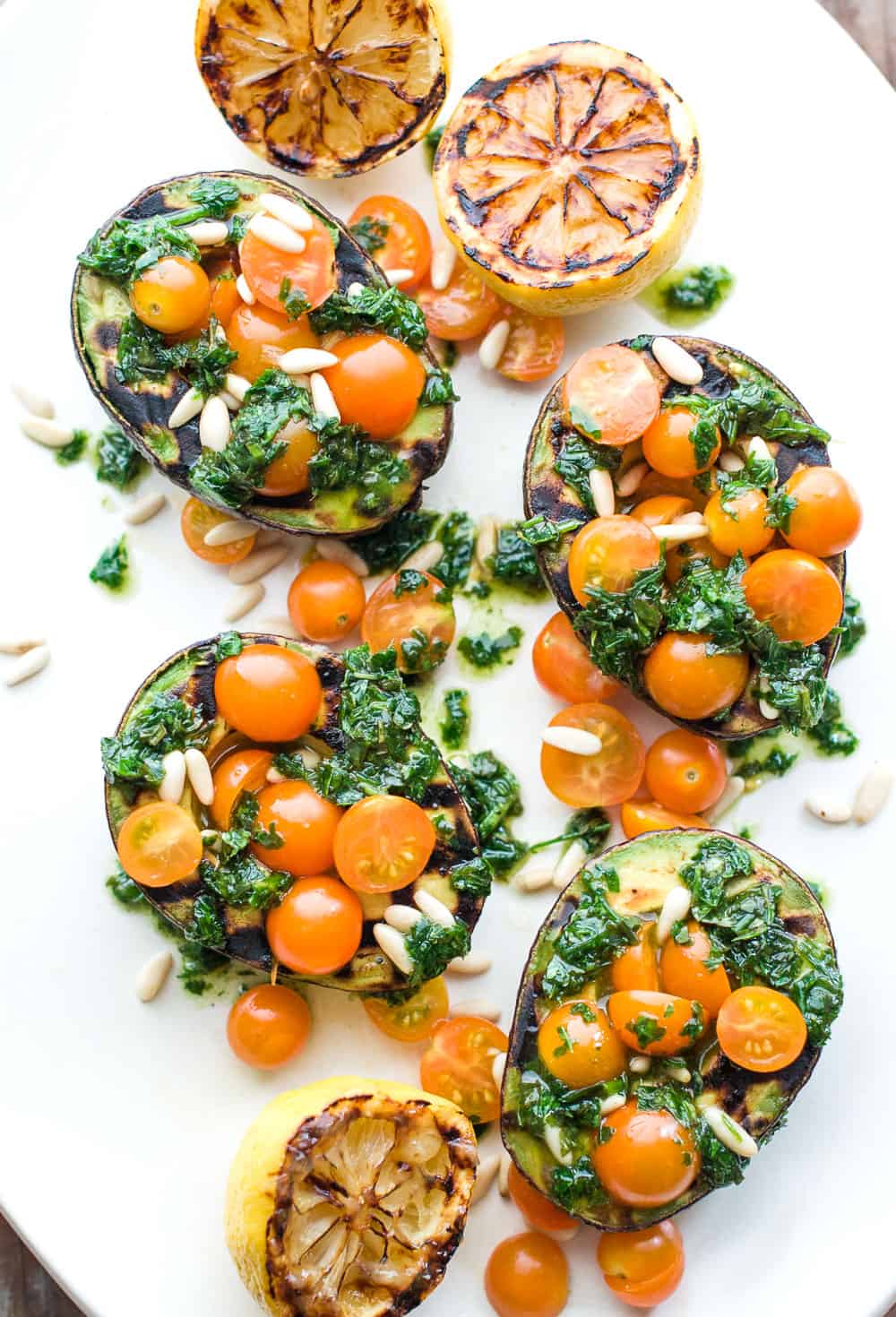 Grilled avocado filled with basil, cherry tomatoes, and pine nuts