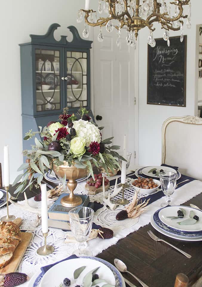 Raised book and vase centrepiece in a burgundy, navy, and gold tablescape