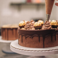 Confectioner decorating chocolate cake, close up 