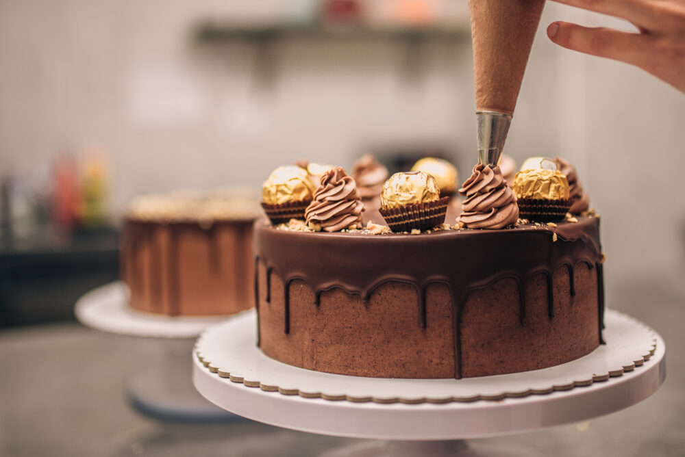 Confectioner decorating chocolate cake, close up