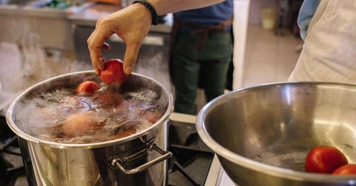 A picture of tomatoes being submerged in boiling water