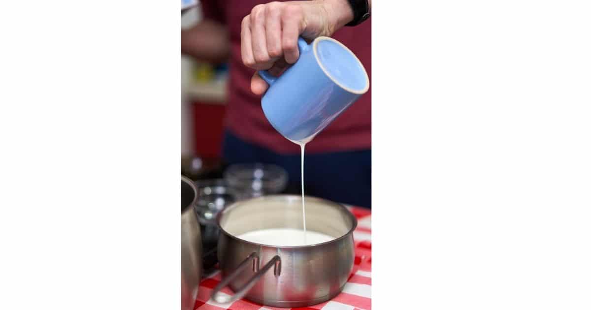 A picture of someone pouring milk in a soucepan - dry cottage cheese