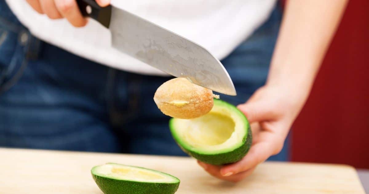 A woman removing the pit of an avocado