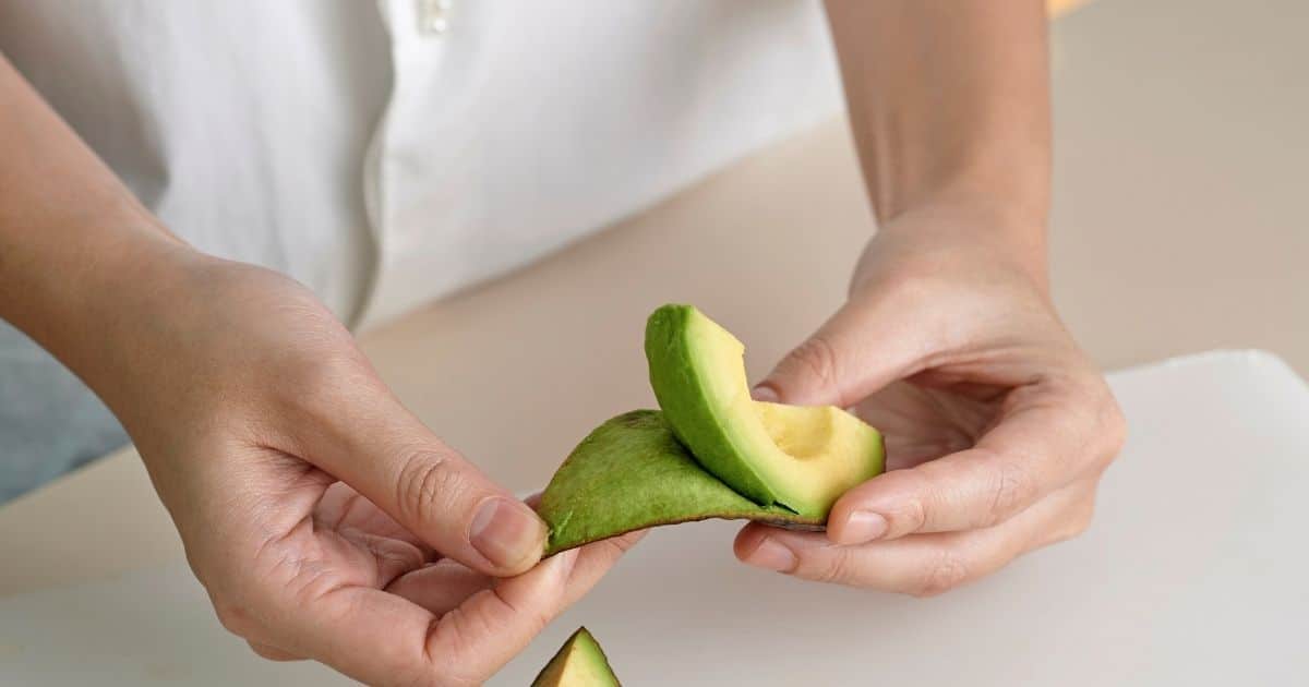 A quarter of an avocado being peeled