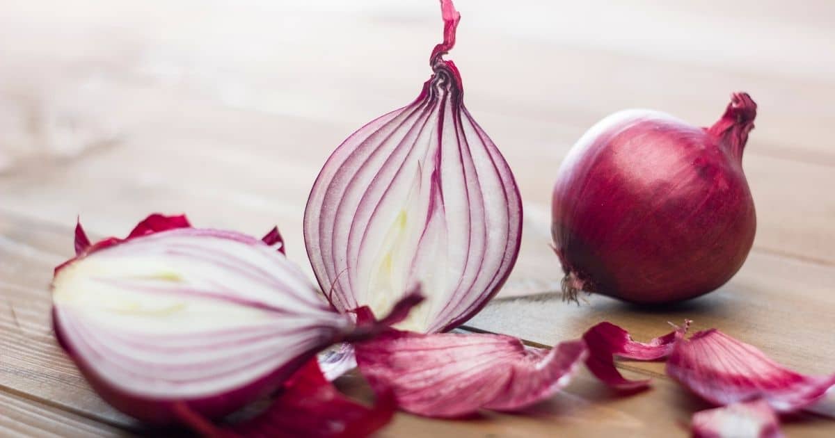Red onions cut half on a wooden desk.