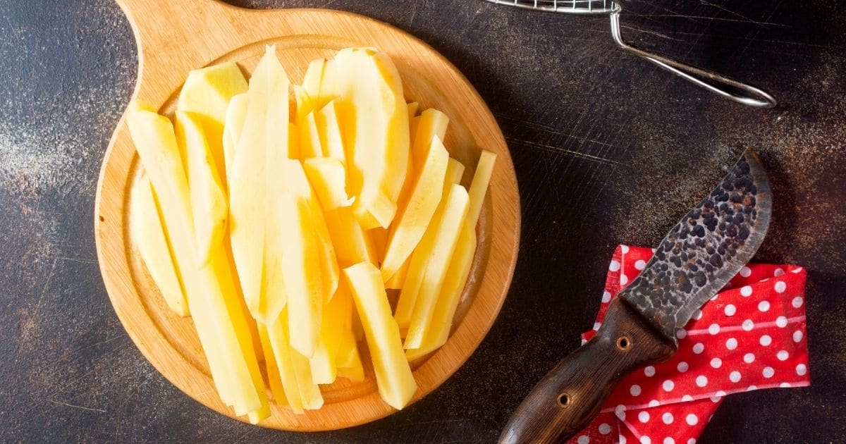 French fries drying at room temperature on top of a wooden chopping board