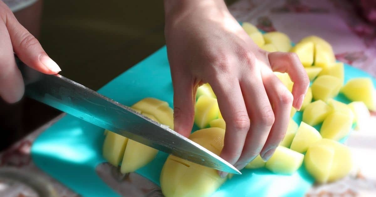 Raw peeled potatoes being cut