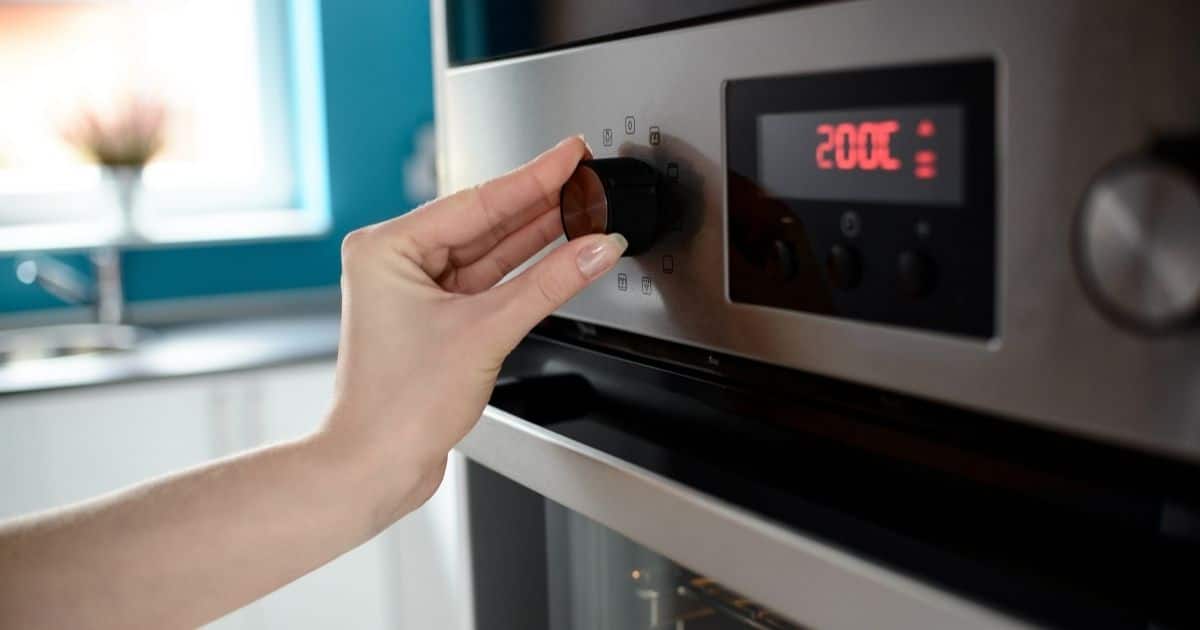 A woman turning on an oven