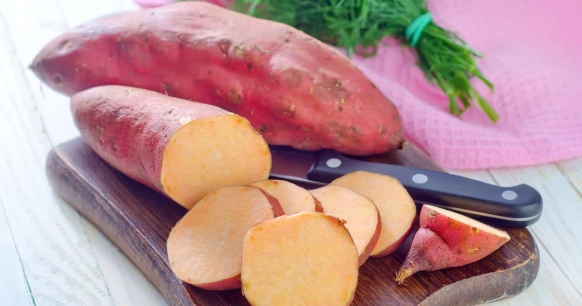 Raw sweet potatoes cut on a cutting board.