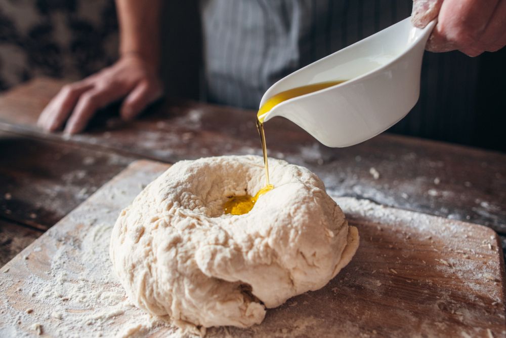 adding olive oil to raw dough